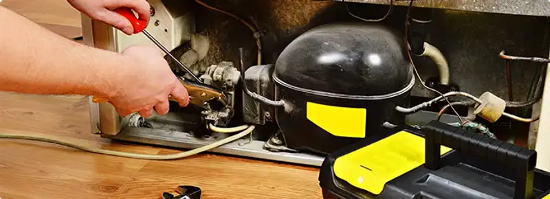 Refrigerator repair technician fixing the compressor and wiring in Norwalk, CT