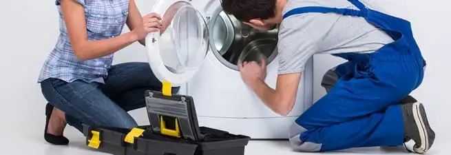 Washer repair technician inspecting a front-load washing machine with tools in Stamford, CT
