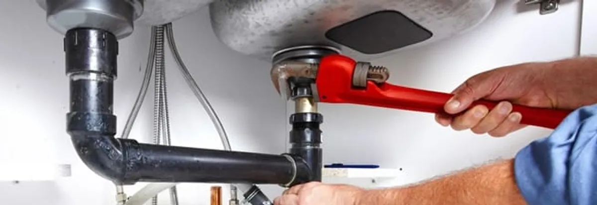 Garbage disposal repair technician tightening the sink drain and disposal connection in Stamford, CT