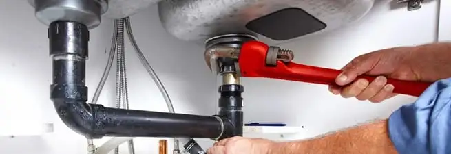 Garbage disposal repair technician tightening the sink drain and disposal connection in Stamford, CT
