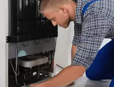 Refrigerator repair technician servicing the compressor and condenser area in Stamford, CT