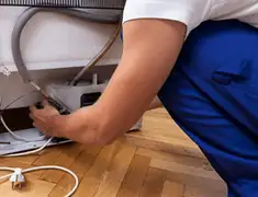 Appliance repair technician fixing refrigerator water line and connections in Stamford, CT