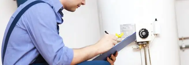Water heater repair technician inspecting the unit and recording service notes in Stamford, CT