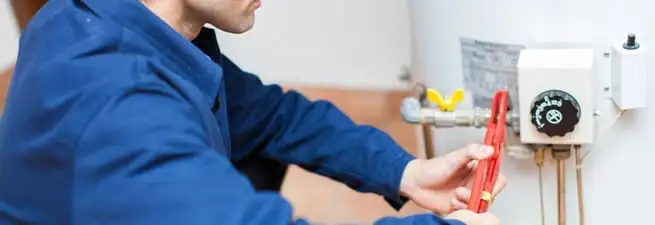 Water heater repair technician adjusting the temperature control and gas valve in Stamford, CT